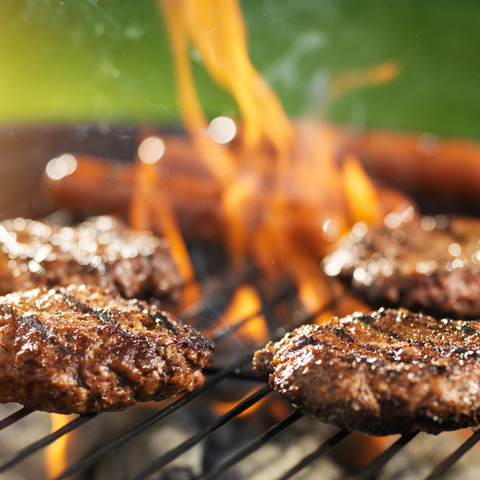 Hamburgers and hotdogs on a flaming  grill