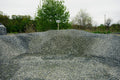 Gravel pile with a sign indicating '2B' in an outdoor setting with trees and sky.