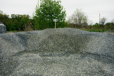 Gravel pile with a sign indicating '2B' in an outdoor setting with trees and sky.