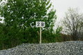Number 2B sign on a gravel hill with trees in the background