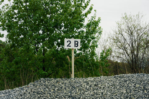 Number 2B sign on a gravel hill with trees in the background