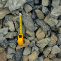 A yellow tape measure extended vertically among gray and beige stones to show size against a pile of rocks.