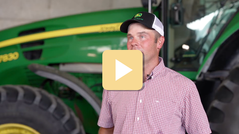Man standing in front of a green tractor with a play button overlay