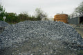 Pile of gravel with a wooden tank and trees in the background