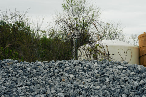 Pile of gray stones with a white container and trees in the background