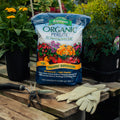 Bag of Espoma Organic Perlite on a wooden table with gardening tools and gloves, surrounded by plants.