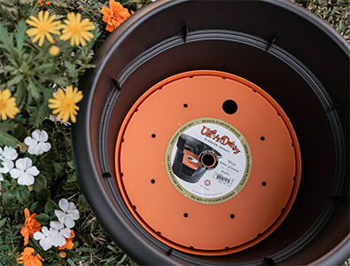 Ups-A-Daisy round planter insert for garden pots, shown placed inside an empty ceramic flower pot for soil conservation.