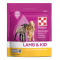 A bag of Purina Lamb & Kid Colostrum Replacer dog food on a plain white background. The packaging is primarily magenta pink with a white and yellow band at the bottom, featuring images of a black lamb and a light brown lamb.