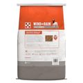 A bag of Wind and Rain Goat Mineral dry dog food, featuring a white bag with a bright orange top section and a gray bottom section.