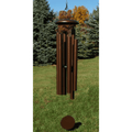 Bronze wind chime on grass with trees in the background