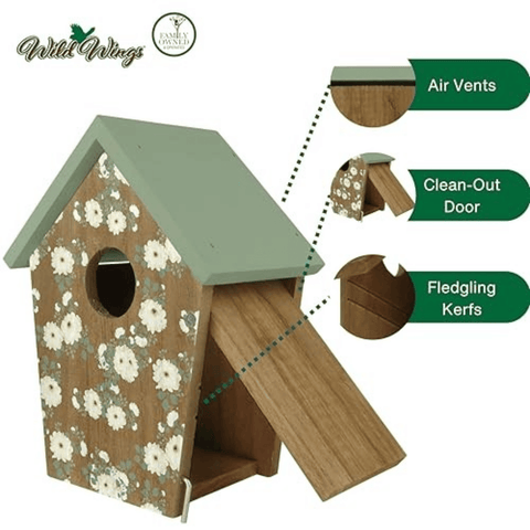 A wooden birdhouse with a sage green roof, floral-patterned brown front panel, and open front door. Callout callouts point to the roof, air vents, clean-out door, and fledgling kerfs.