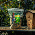 A bag of Mill Backyard Conservation Mix seed mix displayed on a metal garden bench next to a wooden birdhouse, with a garden background.