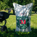 Kentucky 31 Tall Fescue seed bag on a grassy field with a lawn mower in the background.