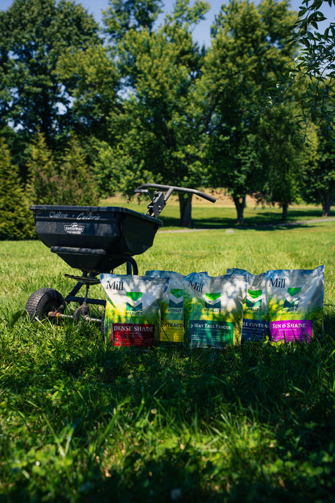 Lawn fertilizer spreader on grass with bags of fertilizer in front