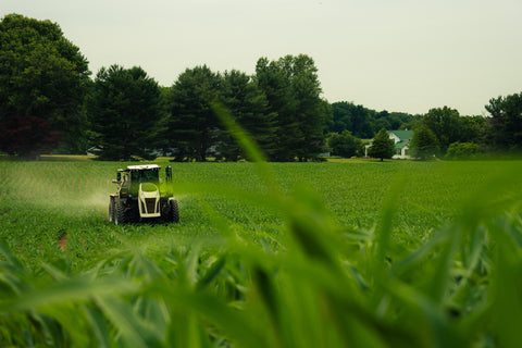 Tractor in a green field with trees in the background