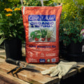 Coast of Maine organic indoor houseplant mix bag on a wooden table with gardening tools and gloves.