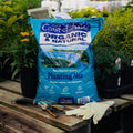 Bag of Coast of Maine Organic & Natural Planting Mix on a wooden table with gardening tools and gloves.