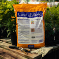 Bag of Coast of Maine in-ground garden soil on a wooden table with gardening tools and gloves.