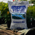 Bag of Coast of Maine Organic & Natural Grower's Mix on a wooden surface with gardening tools and gloves.