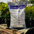 Back of Bag of Coast of Maine Organic & Natural Grower's Mix on a wooden surface with gardening tools and gloves.