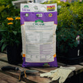 Bag of Organic Bulb-tone fertilizer on a wooden table with gardening tools and plants in the background.
