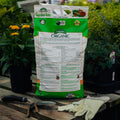 Bag of Garden-tone Organic fertilizer on a wooden table with gardening tools and gloves.