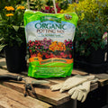 Bag of Espoma Organic Potting Mix on a wooden table with gardening tools and gloves.