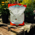 Bag of Espoma Organic Cactus Mix on a wooden table with gardening tools and gloves.