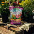 Bag of Espoma Organic Orchid Mix on a wooden table with gardening tools and gloves.
