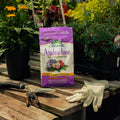 Bag of Organic Azalea-tone fertilizer on a wooden table with gardening tools and gloves.