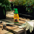 Indoor plant food bottle on a wooden surface with gardening tools and gloves