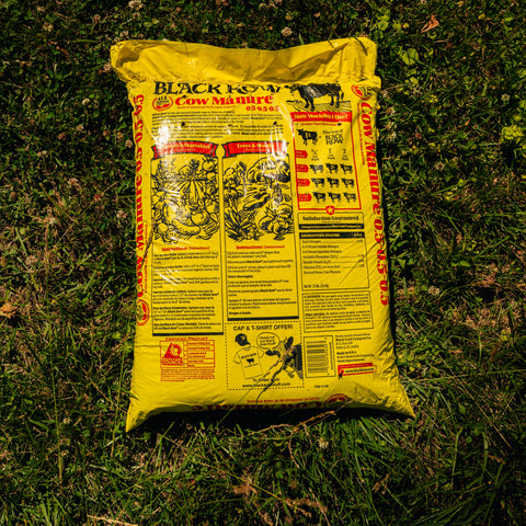 Yellow bag of Black Cow Cow Manure on grass