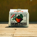 A bag of Lamfert Pest Moss organic soil amendment sits on a wooden deck in front of a wooden wall. The white bag features a prominent black, green, and red label with the Lamfert brand name and pest control icons.