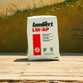 A bag of Lambert LM-AP All Purpose soil conditioner stands on a wooden deck in front of a painted wall with flowers and text.