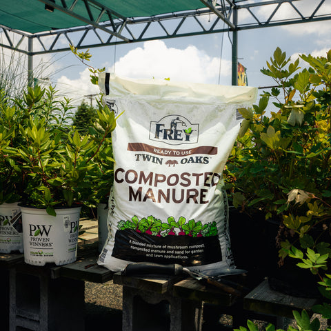 Bag of Twin Oaks Composted Manure with plants in the background
