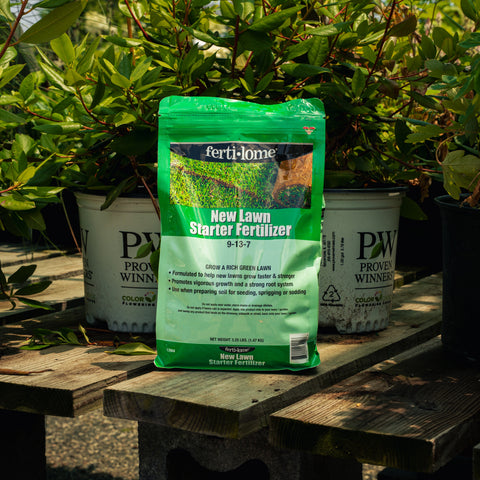 Fertilome New Lawn Starter Fertilizer package on a wooden table with plants in the background