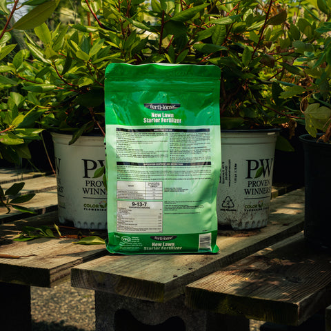 Green fertilizer bag on a wooden table with plants in the background