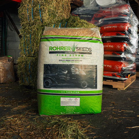 Bag of Rohrer Seeds fine straw in a warehouse setting with hay and other supplies.