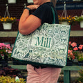 a woman carrying a mill branded tote bag with farm animals printed on it