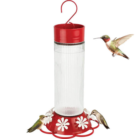 Red hummingbird feeder with a white floral base and a small bird on a white background
