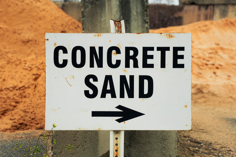 Sign pointing to concrete sand with a pile of sand in the background