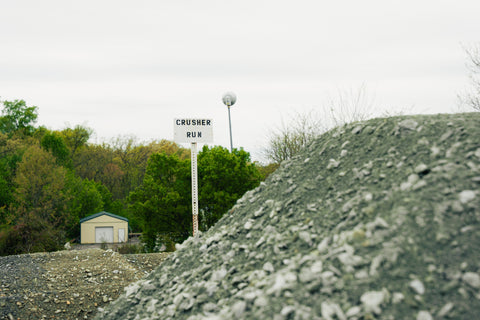 Pile of crushed rock with a sign labeled 'Crusher Run' in the background.