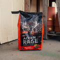A bag of Acorn Rage Deer Attractant stands on a concrete floor in front of a garage door, with stacked terracotta pots visible in the background.