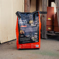 A bag of Acorn Rage Deer Attractant stands on a concrete floor in front of a garage door, with stacked terracotta pots visible in the background.