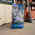 A bag of Big & J Deer Attractant with a wood stand and terracotta vases present 