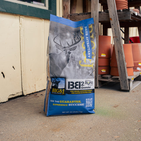 A bag of Big & J Deer Attractant with a wood stand and terracotta vases present 