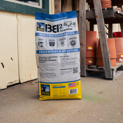 A bag of Big & J Deer Attractant with a wood stand and terracotta vases present 