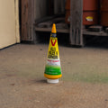 A single Victor brand mole and gopher bait tube standing upright on a concrete floor in a garage or storage area, with wooden beams and barrels blurred in the background.