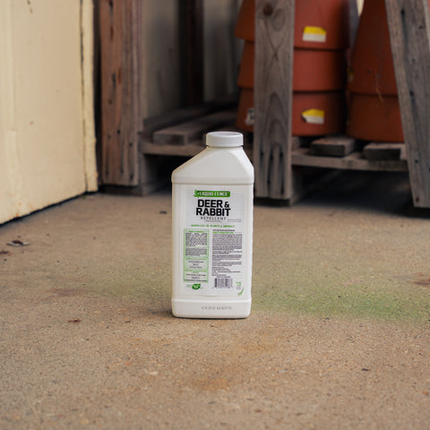 A bottle of Liquid Fence Deer and Rabbit Repellent with a barn background