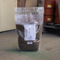 A clear plastic stand-up pouch filled with perennial clover deer plot mix, standing on a concrete floor. 